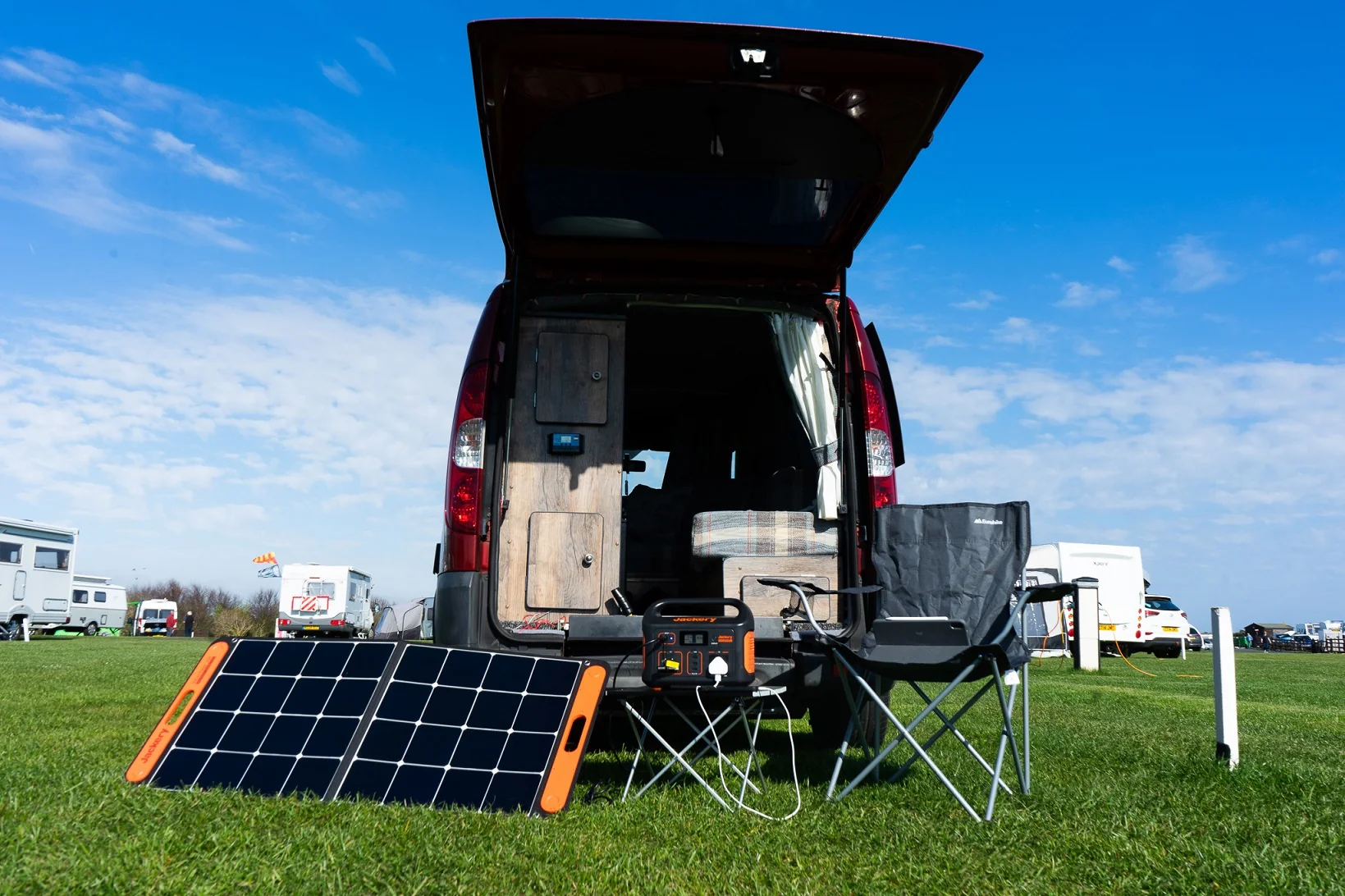 Solar generator kit with folding panels set up beside a camper van